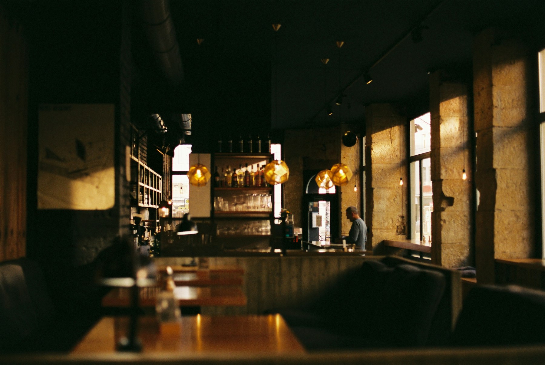 A dimly lit restaurant where warm pendant lighting picks out the tables